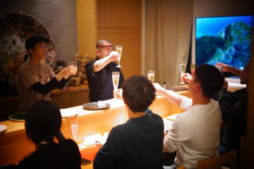 a group of people sitting around a table drinking wine at 泊まる寿司屋一力 Sushi house in Itoshima