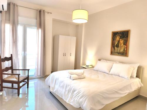 een slaapkamer met een groot wit bed en een stoel bij LUX Central in Alexandroupoli