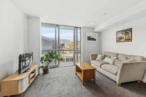 a living room with a couch and a large window at 3-Bedroom CBD Elevate Apartment in Wellington
