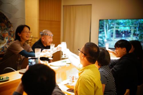 a group of people sitting around a table at 泊まる寿司屋一力 Sushi house in Itoshima