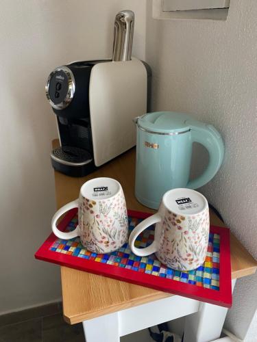 two mugs on a shelf next to a toaster at B&B LE TRE CHIOCCIOLE in SantʼAntìoco