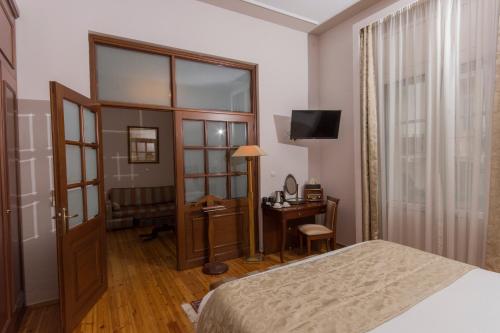 a bedroom with a bed and a desk and a television at Capsis Bristol Boutique Hotel in Thessaloniki