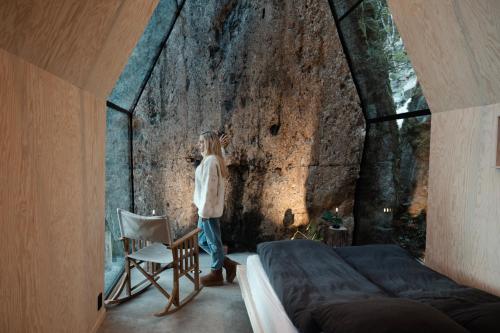 a person standing next to a wall in a bedroom at Spectacular Fjord getaway - The Forge in Leirgulen