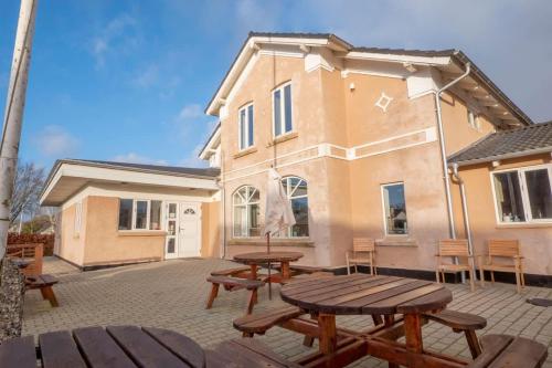 a patio with wooden tables and benches in front of a house at Big Family Home Near Romo Spacious for 30 Guests in Skærbæk