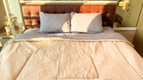 a bed with two pillows and a blanket at Tanglin Tower with Netfix by AquHome in Surabaya