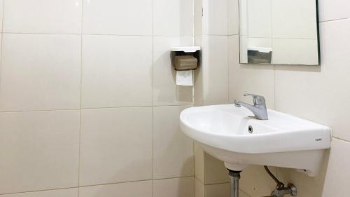 a white bathroom with a sink and a mirror at Tanglin Tower with Netfix by AquHome in Surabaya