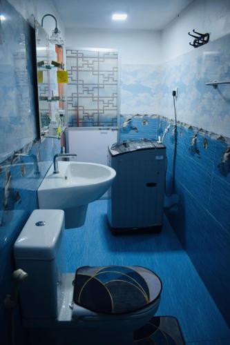 a blue bathroom with a toilet and a sink at Nandana Villa Induruwa in Induruwa