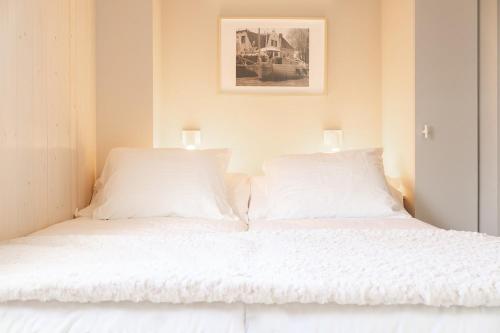 Una cama blanca con dos lámparas encima. en Waterlodge in Heeg - Relax, sail and enjoy!, en Heeg