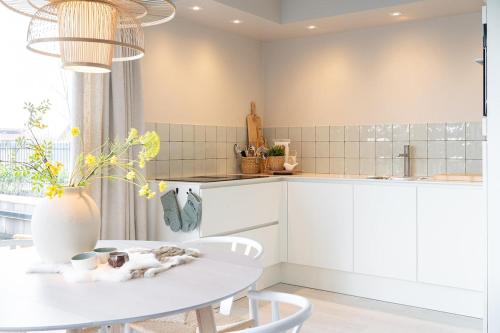Una cocina blanca con una mesa y sillas blancas. en Waterlodge in Heeg - Relax, sail and enjoy!, en Heeg