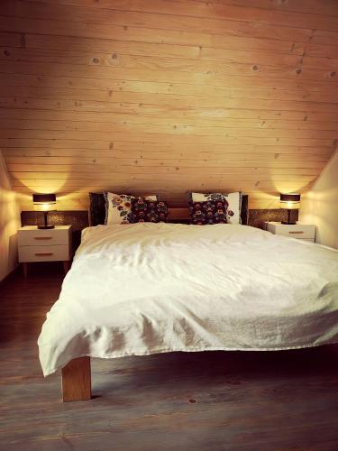 a bedroom with a large white bed with wooden walls at Domek w Poleskim Parku in Urszulin