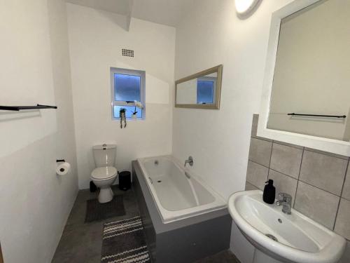 a bathroom with a tub and a toilet and a sink at Low tide living in Struisbaai