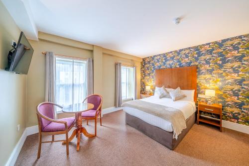 a bedroom with a bed and a table and chairs at The Gateway Hotel in Swinford