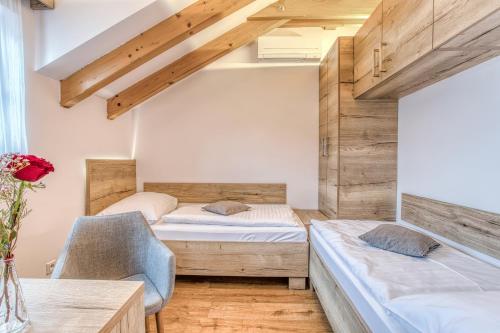 two beds and a chair in a room with wooden walls at Apartmány U Holubů in Rožnov pod Radhoštěm