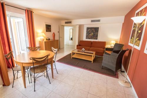a living room with a table and a couch at Cannes Croisette Prestige Apart'hotel in Cannes