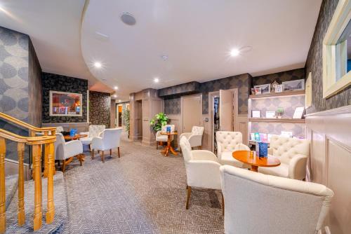 a waiting room with white chairs and tables at The Gateway Hotel in Swinford