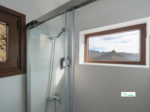 a shower with a glass door with a window at Living Artenara - CAVE HOUSE & SILENCE Adults Only in Artenara