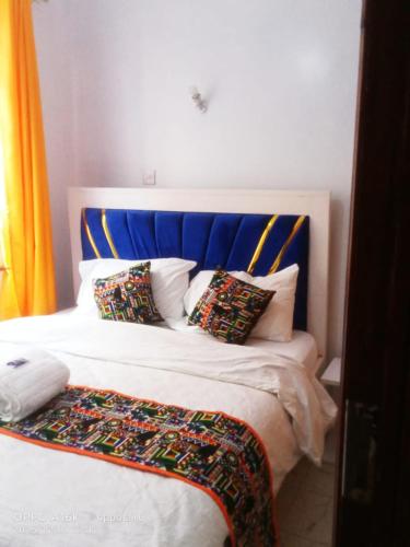 a bed with a blue headboard and pillows on it at Shalom Stays in Machakos