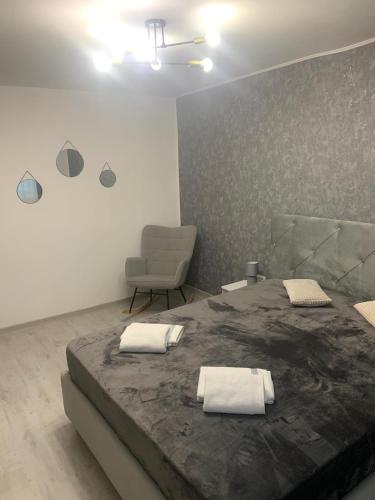 a bedroom with a large bed and a chair at Bia's apartament in Râşnov