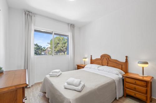 a white bedroom with a bed and a window at Acag 135 in Orihuela