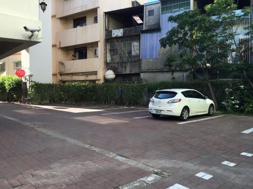 a white car parked in a parking lot in front of a building at The Riverside Hotel & Motel in Kaohsiung