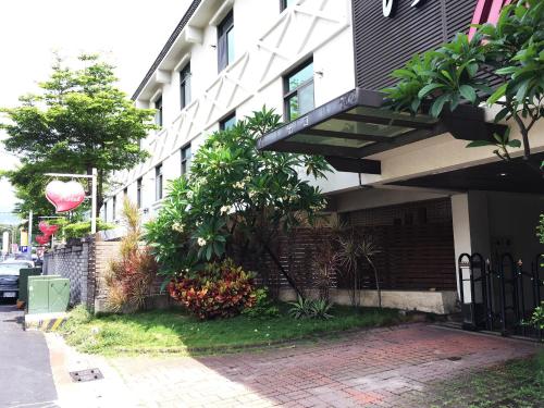 a building with a fence next to a sidewalk at The Riverside Hotel & Motel in Kaohsiung