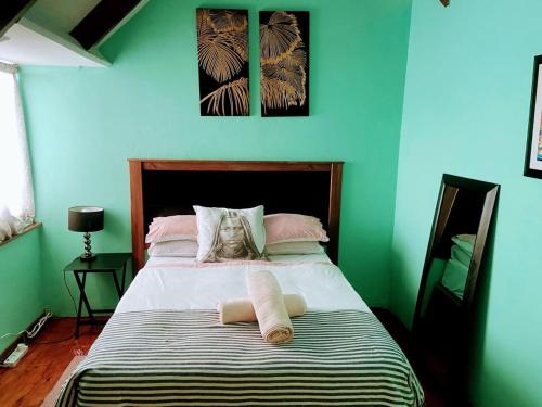 a green bedroom with a bed with two towels on it at Zagorski’s Bed and breakfast in Bloubergstrand