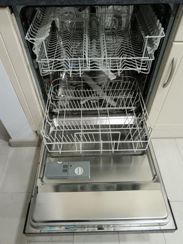 an open dishwasher with racks of dishes in it at Cantinho Familiar a 10 minutos do Aeroporto in São João da Talha