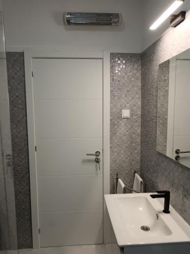 a bathroom with a white shower door and a sink at Cantinho Familiar a 10 minutos do Aeroporto in São João da Talha