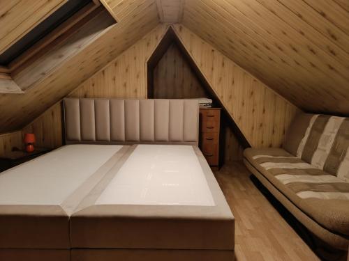 una camera con un letto e un divano in mansarda di Apartamenty pod Jesionami u Bartka a Zakopane