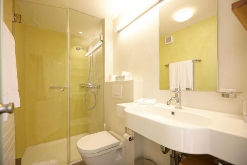 a bathroom with a sink and a toilet and a shower at HOTEL&RESTAURANT Rebstock Wolhusen in Wolhusen