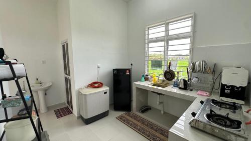 a white kitchen with a stove and a sink at AS Suria Homestay Banglo 1 Tingkat Kota Bharu in Kota Bharu