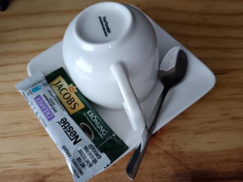 een wit kopje en een lepel op een bord bij 179 Guesthouse on Mountain Drive in Mbabane