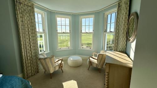 a room with two chairs and a table and windows at 1 Bossiney House - Bude Cornwall in Bude