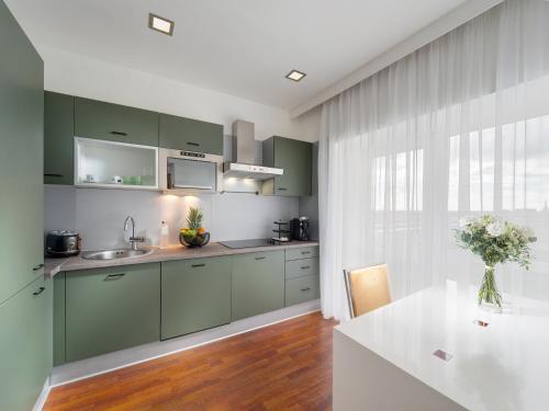 ブラチスラヴァにあるMamaison Residence Sulekova Bratislavaのキッチン(緑のキャビネット、白いテーブル付)