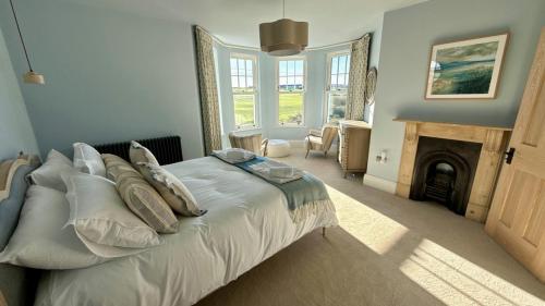 a bedroom with a bed with pillows and a fireplace at 1 Bossiney House - Bude Cornwall in Bude