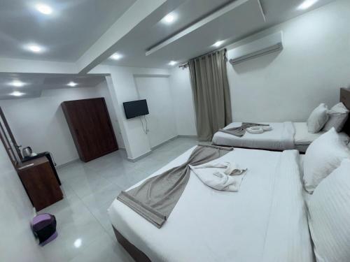 a hotel room with two beds and a flat screen tv at Prince Pyramids Hotell in Cairo