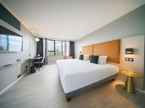 a bedroom with a large white bed and a desk at Maek Hotel Antwerp Central - Handwritten Collection by Accor in Antwerp