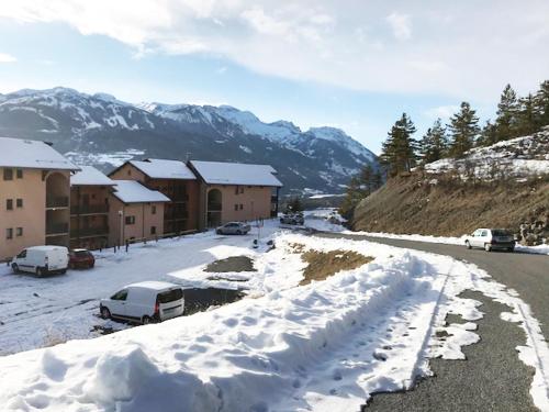 a snow covered street with cars parked in front of buildings at Appartement Hauteur Barcelonnette Vue Exceptionnelle in Barcelonnette