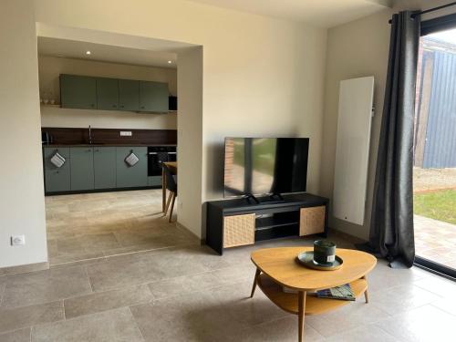 ein Wohnzimmer mit Flachbildfernseher und Tisch in der Unterkunft Les Gîtes du Colombier in Ollé