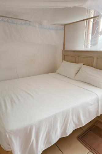 a white bed in a room with a window at Creek apartment in Kilifi