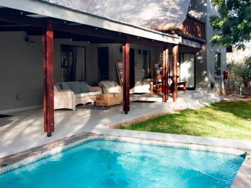 a backyard with a swimming pool and a house at Nzenga Lodge in Hoedspruit