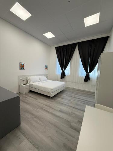 a white bedroom with a bed and a large window at Viva Residence in Calderara di Reno