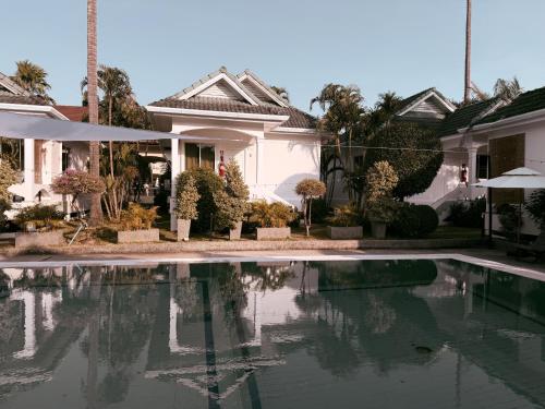 a house with a swimming pool in front of it at The Rai Resort Rawai - Pool & Garden in Ban Bang Chak
