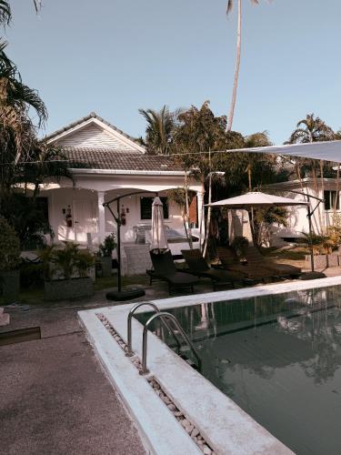 a house with a swimming pool with chairs and umbrellas at The Rai Resort Rawai - Pool & Garden in Ban Bang Chak