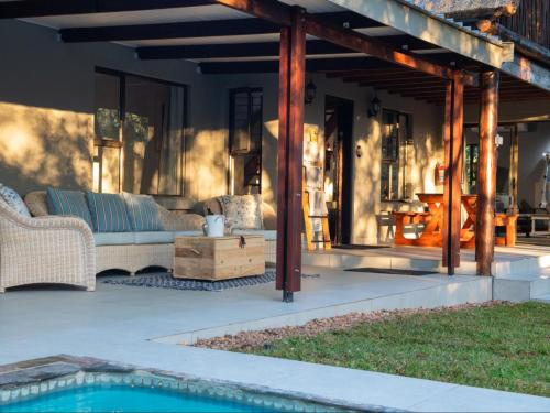 a covered patio with a couch and a table at Nzenga Lodge in Hoedspruit