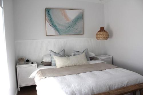 a bedroom with a white bed with a picture on the wall at Beach Bound-Jervis Bay in Vincentia