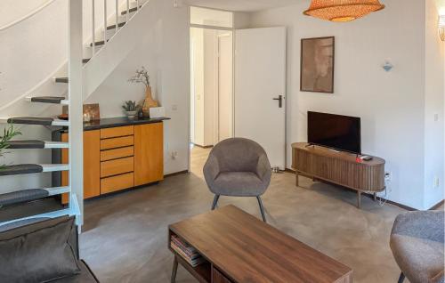 a living room with a chair and a television and stairs at Three Bedroom Nice Home In Hoeven in Hoeven
