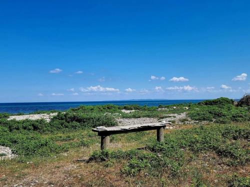 a bench sitting in the grass near the ocean at 6 person holiday home in Dronningmølle-By Traum in Gilleleje