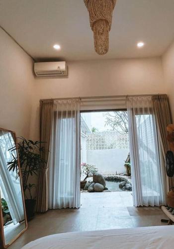 a bedroom with a bed and a large sliding glass door at Chic 2BR Villa w/Rock Plunge Pool in Denpasar
