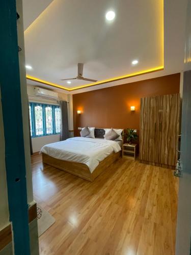 a bedroom with a large bed and a wooden floor at Karma Stay 2BHK apartments in Jaigaon